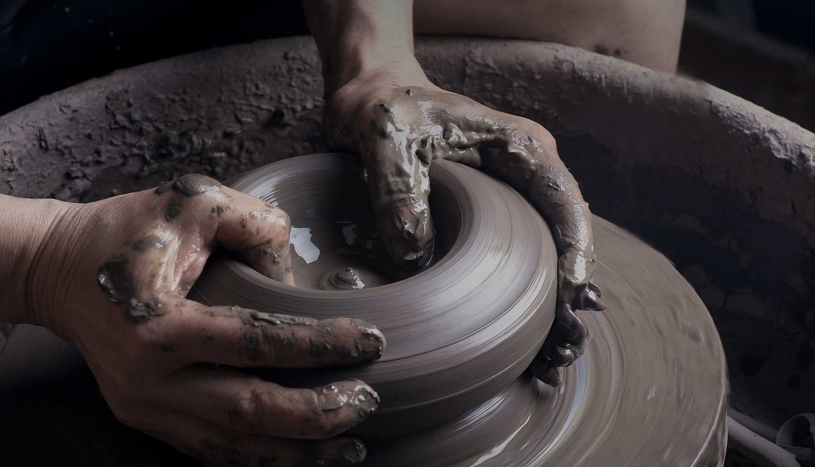 Hands shaping clay on a pottery wheel
